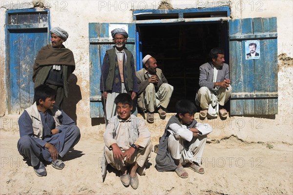 AFGHANISTAN, between Yakawlang and Daulitiar, Syadara, Group of men and young boys sat around a doorway.