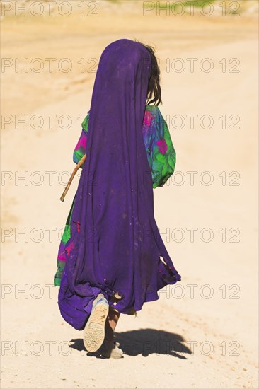 AFGHANISTAN, between Chakhcharan and Jam, Desert, Kuchie nomad girl walking behind camel train