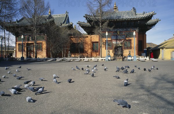 MONGOLIA, Ulaan Baatar, Gandan Hiid Buddhist monastery exterior facade with pigeons in courtyard in foreground.