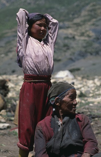 NEPAL, Mustang, Nomads, "Tibetan nomads.  Elderly seated woman with young girl standing behind with arms raised behind head, both looking away to right."