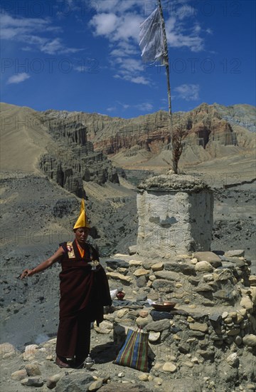 NEPAL, Mustang, Lo Manthang, Tibetan Buddhist monk making offerings of incense at a stupa during Lok Khor ceremony in which prayers are made for a good harvest and protection of the home.