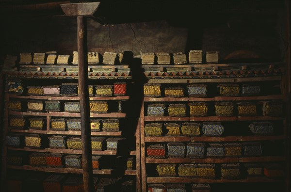 NEPAL, Mustang, Tsarang, "Ancient sacred texts stored in library of old palace of Tsarang, their volumes kept between intricately carved covers."