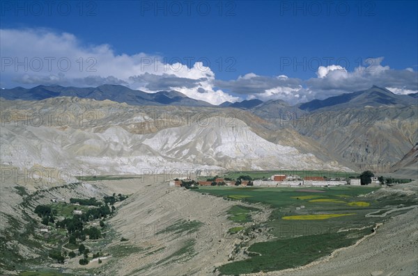 NEPAL, Mustang, Lo Manthang, "Distant view of Mustang’s capital Lo Manthang surrounded by green, cultivated fields and mountain backdrop."