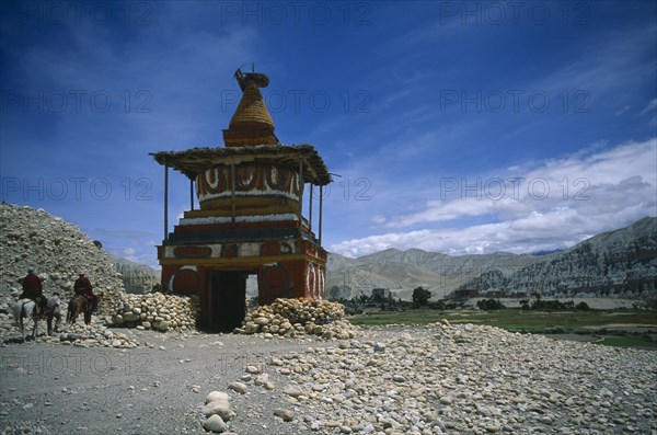 NEPAL, Mustang, Tsarang, "Old, painted stupa marking entrance to Tsarang with two horsemen approaching."