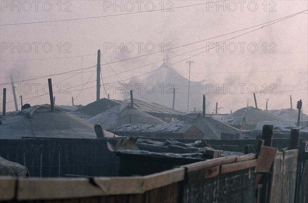MONGOLIA, Ulan Bator, Yurt district with shadowy grey rooftop of the Gandan Monastery behind in winter.