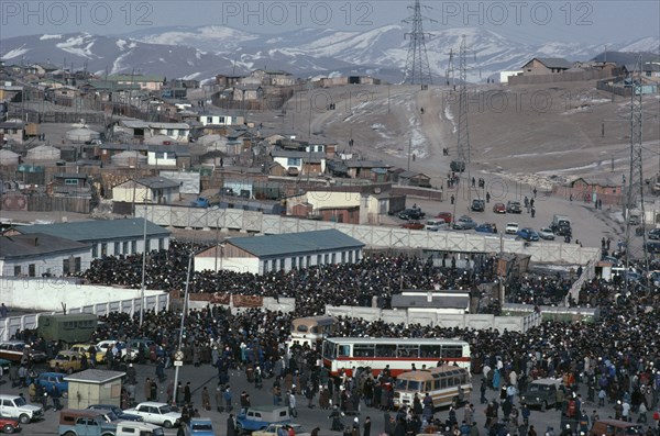 MONGOLIA, Ulan Bator, View over crowded Sunday market with houses stretched across hillside above and line of pylons.