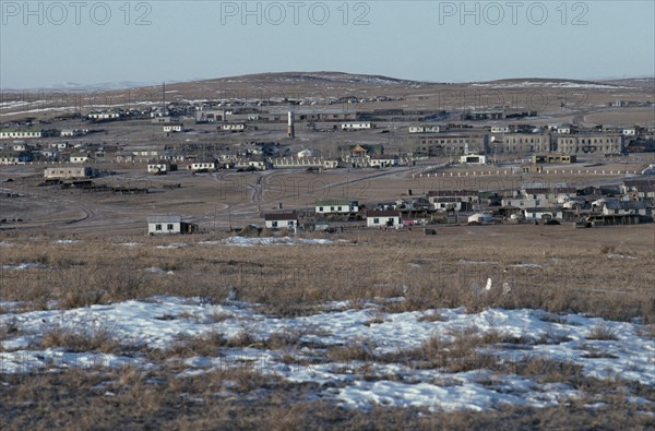 MONGOLIA, Gobi Desert, Tsagaan Ovoo, View towards typical small town in open landscape with patches of melting snow in the foreground.