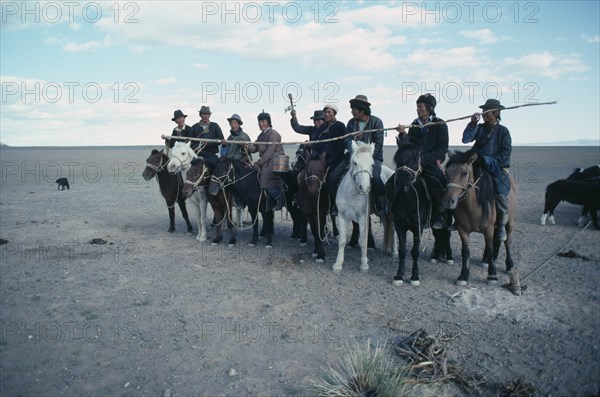 MONGOLIA, South Gobi, Festival, Young herdsmen circling camp abreast on horseback for ceremony of libation of first mare’s milk of the season.