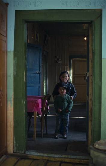 MONGOLIA, North, Children, Brother and sister standing in open doorway of home with green painted door frame.