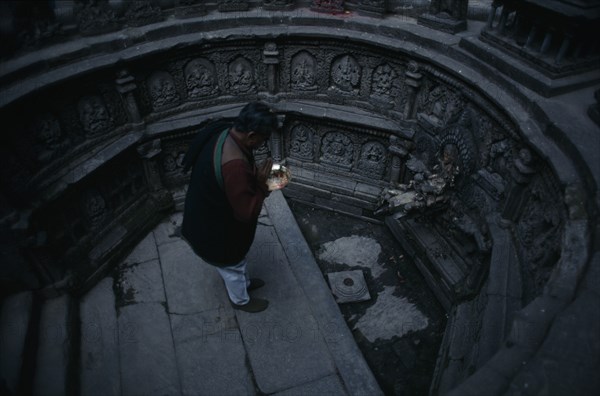 NEPAL, Kathmandu, "Man worshipping in sunken tank and former royal bath known as Tusha Hiti in Sundari Chowk, Mangal Bazar.  Originally built c. 1670 and restored 1960."