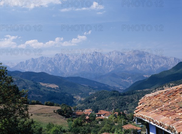 SPAIN, Cantabria, Cabezon de Liebana, "View towards the Picos de Europa mountains in northern Spain from the Posada la Trebede, Perrozo. Tiled rooftops of village and the Val de Liebana valley."