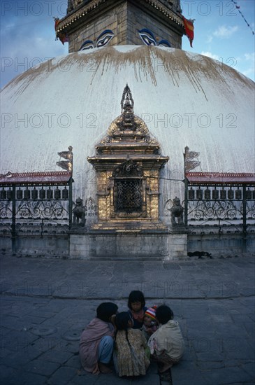 NEPAL, Kathmandu, Small group of children with baby crouched together on ground in front of Swayambhu Stupa.