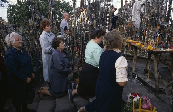 LITHUANIA, Hill of Crosses, Men and women pray in front of hundreds of crosses and crucifix at ancient pilgrimage site near Siaulial.