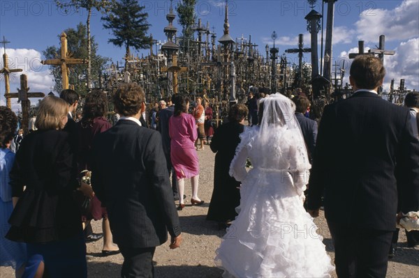 LITHUANIA, Hill of Crosses, Wedding group in front of hundreds of crosses and crucifix at ancient pilgrimage site near Siaulial.