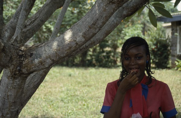 NIGERIA, Ibadan, Portrait of Yoruba girl eating groundnuts.