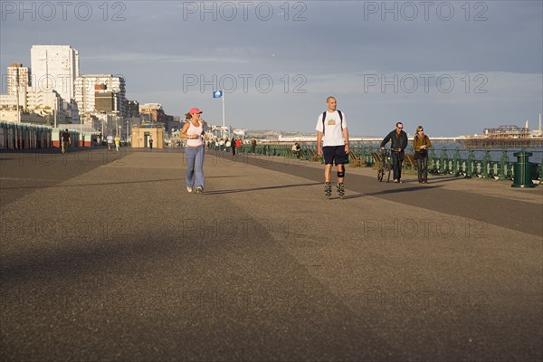 ENGLAND, East Sussex, Brighton, Woman jogging with man rollerblading on the seafront promenade.