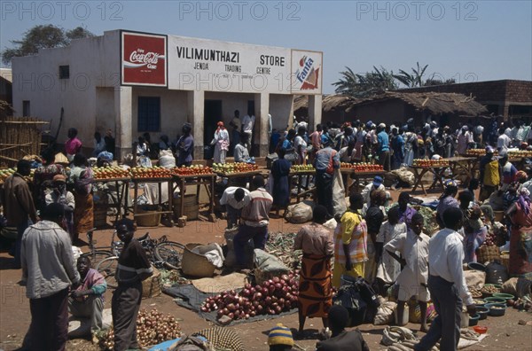 MALAWI, Jenda, "Crowded market scene, fruit and vegetable stalls with trading centre building behind."
