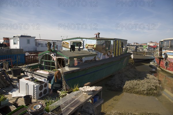 ENGLAND, West Sussex, Shoreham-by-Sea, "Houseboat moored along the banks of the river adur.  Former barges converted into homes with the use of various bits of junk, including cars, buses and washing machines."