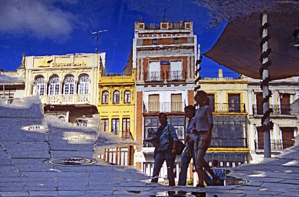 SPAIN, Andalucia, Seville, Reflection of buildings and pedestrians in Plaza de San Francisco.