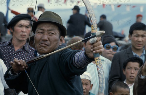 MONGOLIA, Ulan Bator, Nadam  National Day celebrations  archery competition in Ulan Bator stadium  competitor flexes Mongolian longbow to fire at target