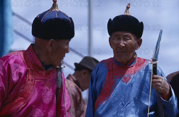 MONGOLIA, Ulan Bator, Nadam  National Day celebrations 2 veterans in fine traditional tunics and hats chatting before archery competition in Ulan Bator stadium