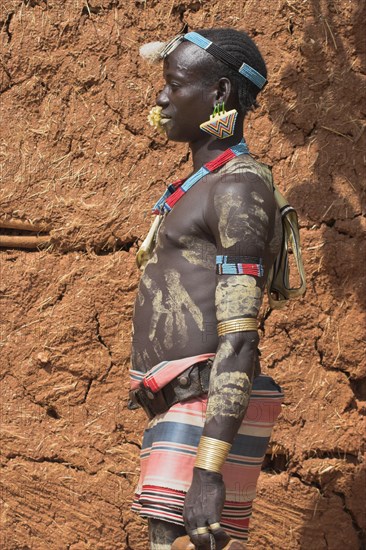 ETHIOPIA, Lower Omo Valley, Key Afir, Tsemay man iwith flower in mouth at weekly market