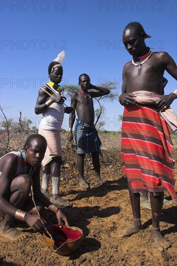 ETHIOPIA, Lower Omo Valley, Tumi, "Dombo village, Hamer man stirring cows bood ready for drinking"