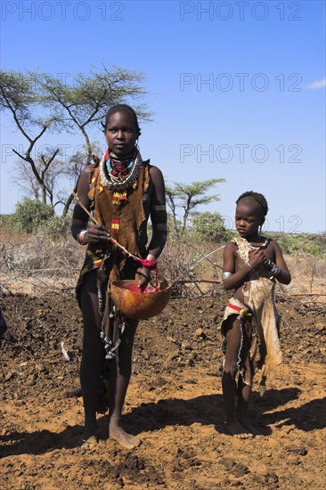 ETHIOPIA, Lower Omo Valley, Tumi, "Dombo village, Child watching Hamer lady stirring cows bood ready for drinking"