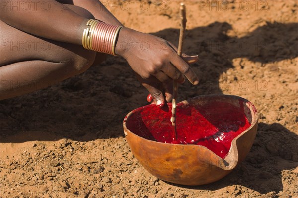 ETHIOPIA, Lower Omo Valley, Tumi, "Dombo village, Hamer lady stiring cows blood ready for drinking"