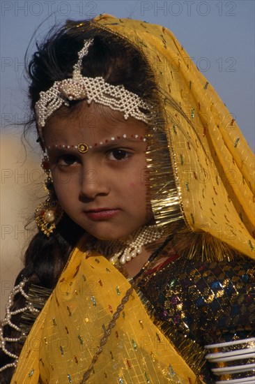 INDIA, Rajasthan, Jaisalmer, Portrait of a young girl wearing yellow with make up and jewellery an entrant in the Miss Desert Competition at the Mini Maru Mela Festival.