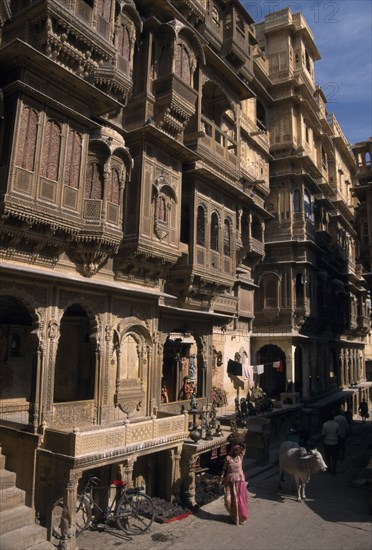 INDIA, Rajasthan, Jaisalmer, Patwon ki Haveli exterior with people and cattle seen on the path at the bottom