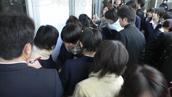 JAPAN, Honshu, Tokyo, "Chiba, Sosa - Yokaichiba Kei Ai High School, 14 and 15 year old third year junior high school students check to see if their number is posted meaning they passed trhe high school entrance exam"