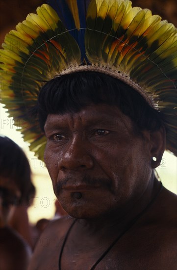 BRAZIL, Mato Grosso, Indigenous Park of the Xingu, Portrait of respected Panara elder  Krekon  wearing crown or head-dress of feathers. Formally known as Kreen-Akrore  Krenhakarore  Krenakore  Krenakarore  Amazon American Brasil Brazilian Indegent Kreen Akore Latin America Latino South America One individual Solo Lone Solitary