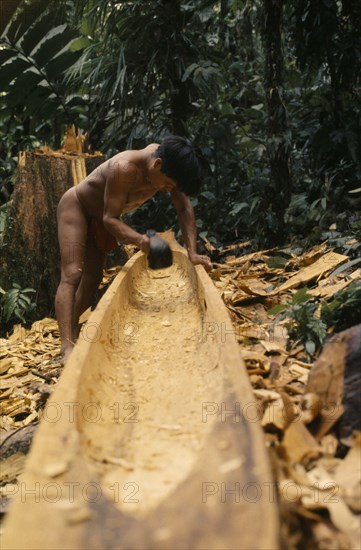 COLOMBIA, Choco, Embera Indigenous People, Embera man using axe or adze .  to hollow out dug out canoe from large felled hardwood tree. Once completed canoe is dragged through forest to riverside home where final shaping takes place Pacific coastal region boat canoa tribe American Colombian Colombia Hispanic Indegent Latin America Latino Male Men Guy South America  Pacific coastal region boat piragua  tribe American Colombian Columbia Hispanic Indegent Latin America Latino Male Men Guy South America Male Man Guy One individual Solo Lone Solitary 1 Single unitary