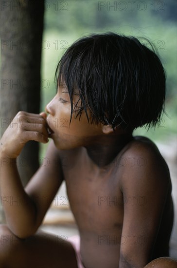 COLOMBIA, Choco, Embera Indigenous People, "Portrait of Embera boy with typical fringe haircut sitting at entrance to stilted family home. Faint body decoration marks from purple/black dye extracted from Jagua fruit, still visible ten days after ceremony. Pacific coastal region tribe.  Pacific coastal region tribe 10 American Children Colombian Columbia Hispanic Immature Indegent Kids Latin America Latino One individual Solo Lone Solitary South America Single unitary Young Unripe Unripened Green "