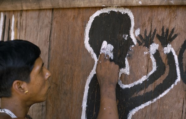 COLOMBIA, North West Amazon, Tukano Indigenous People, Cropped shot of Barasana Indian painting spirit guardian on front of maloca  communal home. Tukano sedentary tribe Indian North Western Amazonia maloca American Colombian Columbia Hispanic Indegent Latin America Latino South America Tukano One individual Solo Lone Solitary Religion