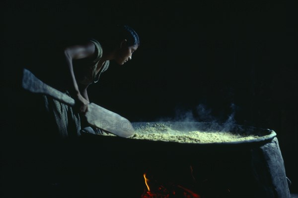 COLOMBIA, North West Amazon, Tukano Indigenous People, Barasana woman making casabe bread from manioc cooked on large circular shallow clay oven over wood fire enclosed by clay oven wall. Tukano sedentary Indian tribe North Western Amazonia cassava American Colombian Columbia Female Women Girl Lady Hispanic Indegent Latin America Latino South America Tukano Female Woman Girl Lady One individual Solo Lone Solitary