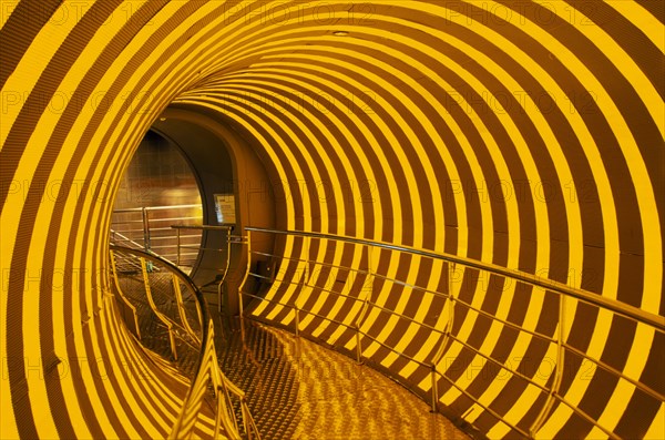 CHINA, Shanghai, Covered walkway at entrance to the Science Museum in Pudong.  Yellow light reflected in shiny metal surfaces.