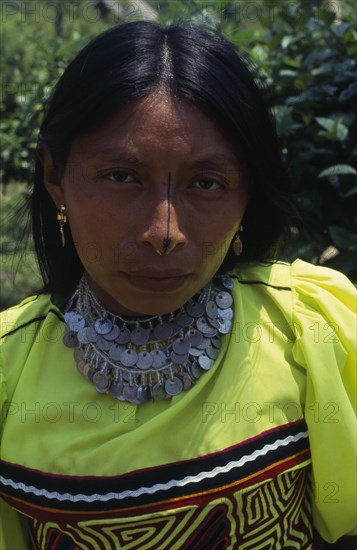 COLOMBIA, Darien, Kuna Indians, Head and shoulders portrait of Kuna woman from the Arquia community wearing gold nose ring  necklace of old Colombian and Panamian coins and traditional mola design applique panel and facial decoration consisting of black stripe running the length of the nose.  Cuna dulemola American Classic Classical Colombian Columbia Female Women Girl Lady Hispanic Historical Latin America Latino Older South America