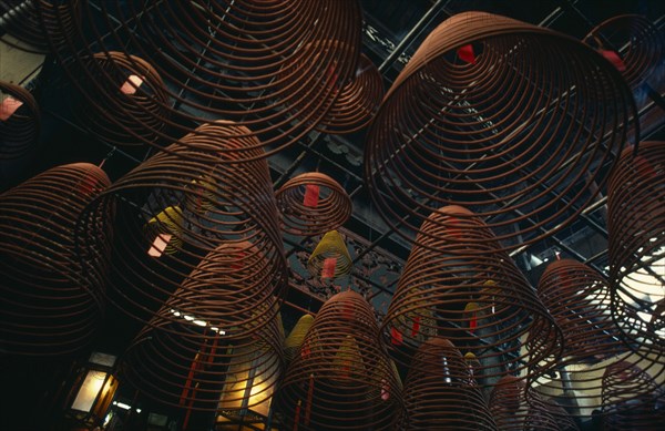 HONG KONG, Central District, Man Mo Temple, Spiral cones of incense hanging from roof of the Man Mo or warlord temple.  The warlord god is Kwan Tai and is patron of both police and gangsters.  A historical figure from the Three Kingdoms period (AD 220-265) he was deified as a Taoist symbol of integrity and loyalty.  The temple is dedicated jointly to Kwan Tai and the god of literature.