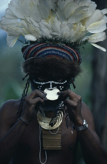 PAPUA NEW GUINEA, Mount Hagen, People, "Portrait of man wearing traditional dress and jewellery, and elaborate white feather and fur trimmed head-dress, with white disc in nose and black and white face paint. "