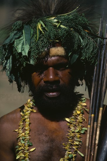 PAPUA NEW GUINEA, Goroka, Head and shoulders portrait of man wearing head-dress made from leaves and vegetation with fur band around forehead and double strand necklace of leaves.