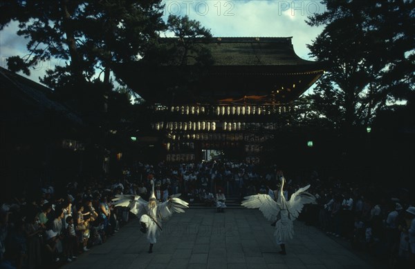JAPAN, Honshu, Kyoto, "Gion District, Yasaka Shrine.  Performance of the Dance of the White Herons in outside courtyard watched by large crowd.  Believed to have originated in the ninth century as a feature of Shinto rituals to rid Kyoto of disease, remains part of the festival activities to this day."