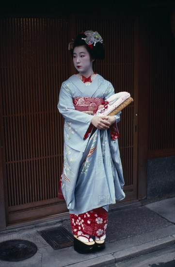 JAPAN, Honshu, Kyoto, "Someiyu, a maiko or apprentice geisha standing in the doorway of a geisha house in the Gion District.  Her client will pay nearly £100 for the pleasure of her company. "