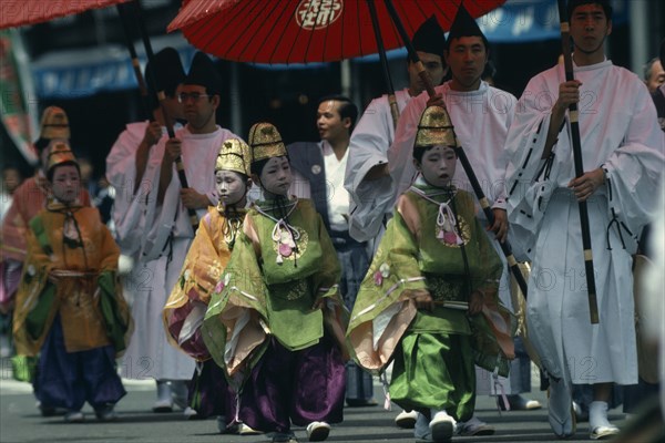 JAPAN, Honshu, Kyoto, Gion Festival.  Pageboys in elaborate costume parade in festival procession shielded from the sun by paper parasols carried by their attendants.