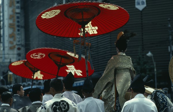 JAPAN, Honshu, Kyoto, "Gion Festival.  Four days before the festival climax the ‘chigo’ the pageboy of the god to whom the festival is dedicated, dressed in the silk robes of a Heian nobleman is taken on a white horse to a ceremony of exorcism and purification in the Yasaka shrine.  He is shielded from the sun by red parasols carried by attendants."