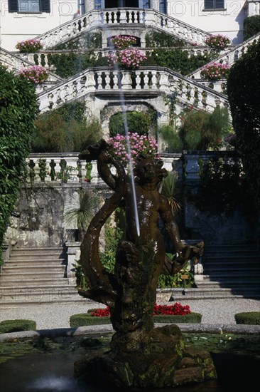 ITALY, Lombardy, Lake Como, Villa Carlotta eighteenth century summer-house near Tremezzo.  Fountain and gardens in foreground with steps to tiered balconies leading to villa behind.