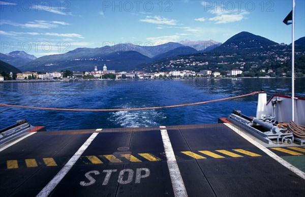 ITALY, Piedmont, Pallanza, View across Lake Maggiore towards shoreline and Pallanza from the ferry with warning Stop sign on ferry deck in foreground and rope across end.