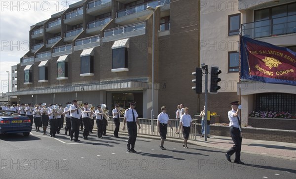 ENGLAND, West Sussex, Worthing, The Salvation Army Band marching along seafront with flags flying in the summer.