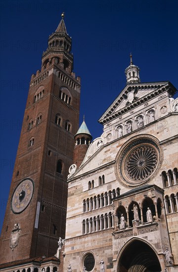ITALY, Lombardy, Cremona, Piazza del Comune.  Part view of the Duomo facade and rose window beside medieval bell tower known as the Torrazzo and linked together by a Renaissance loggio.